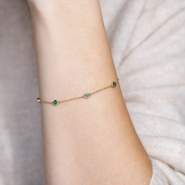 Shown with Lab Created Emerald Gemstones in 14K Yellow Gold|Woman wearing Emerald Bezel Station Chain Bracelet in 14 carat Yellow Gold from Lab Grown Gemstone specialists MiaDonna 